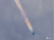 虹色に染まる飛行機雲が大空を貫く        